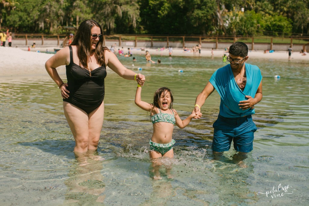 Babywearing family playing together in the water.