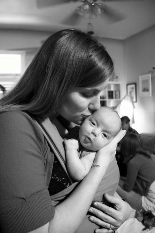 Twin Mom in a Wrap Wrapped baby getting kissed.